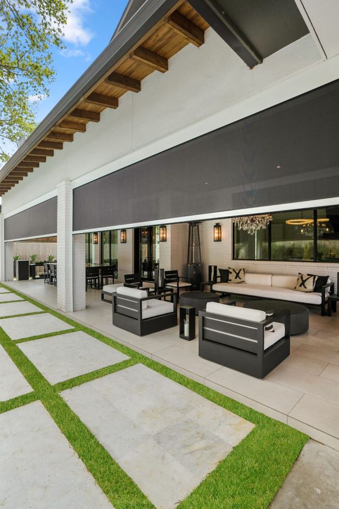 Modern outdoor patio with gray furniture, white walls, and grass-lined concrete