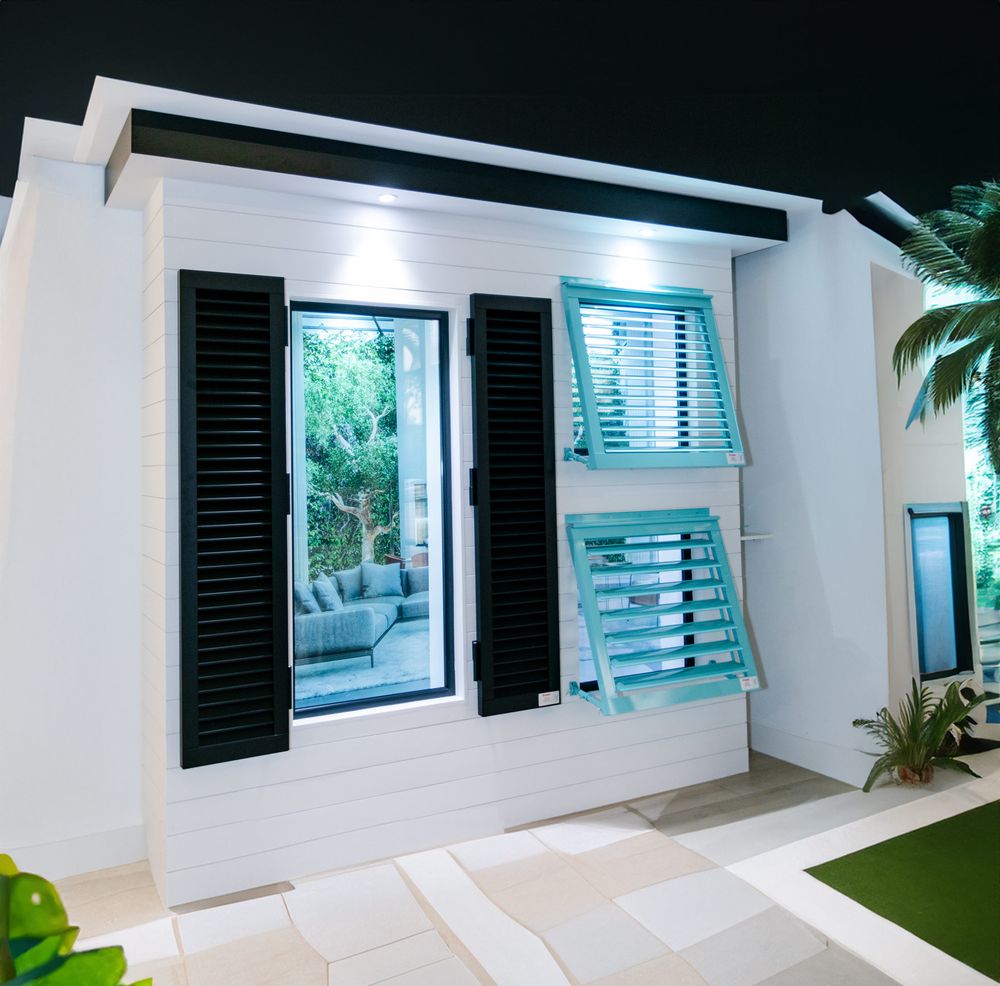 Modern white house exterior with turquoise window shutters and lush greenery